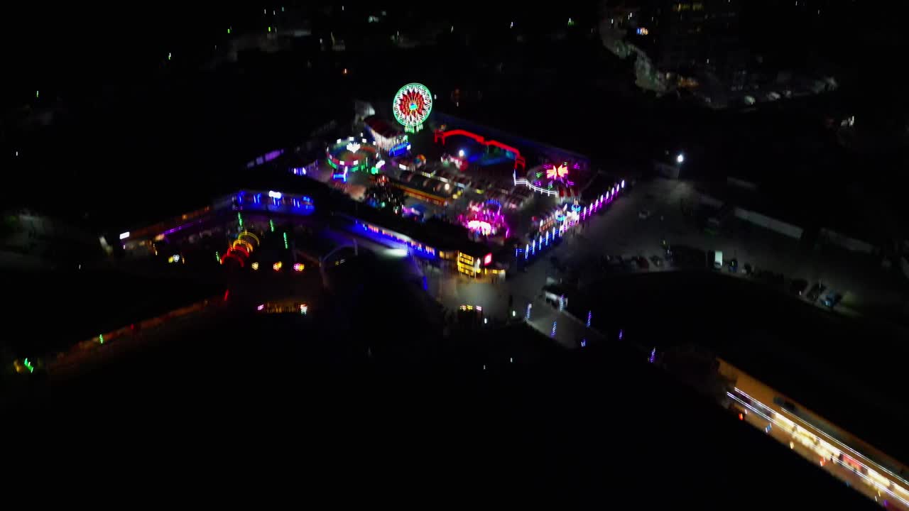 Aerial tilt reveal of colorful pop-up carnival and amusement park during evening at provincial town of Virac, Catanduanes, Philippines.