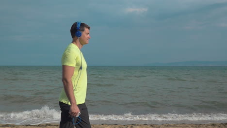 Mann-Joggt-Mit-Smartphone-Am-Strand