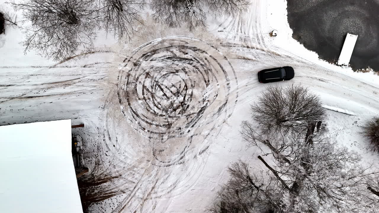 Vista dall'alto di un veicolo che fa drifting in cerchio su una strada ghiacciata