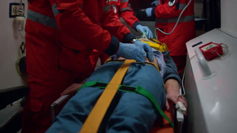 paramedics giving first aid to patient in ambulance car. doctor examining man