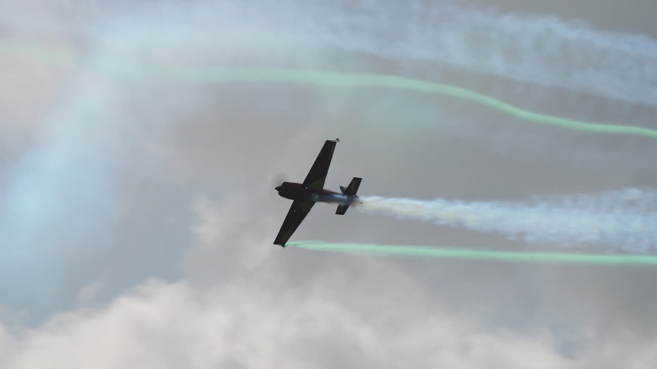 Single aerobatic airplane performing a curved smoke trail stunt in the sky during flight show