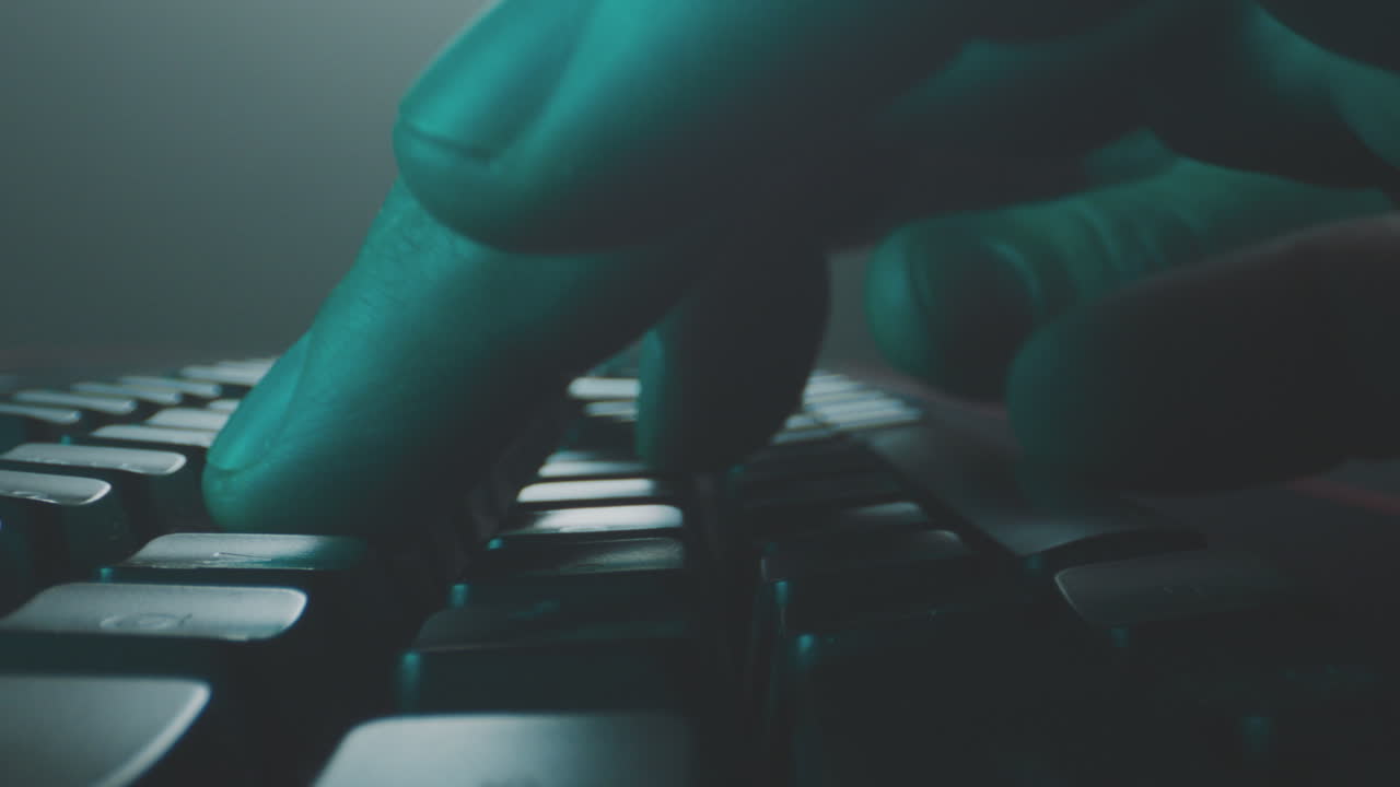 persona escribiendo en un teclado con guantes azules