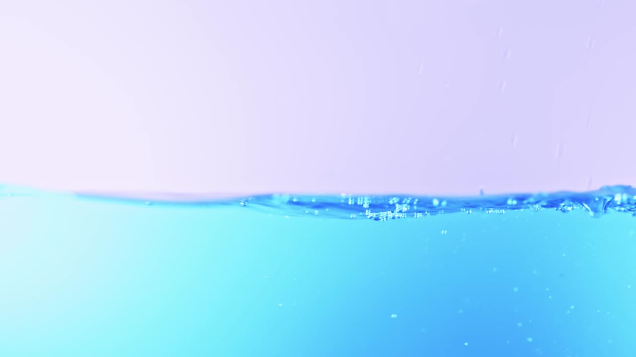 슬로우 모션의 깨끗한 물 표면은 물이 튀는 상점으로 화면을 채우고 기포로 액체 표면을 흔들고 있습니다.
