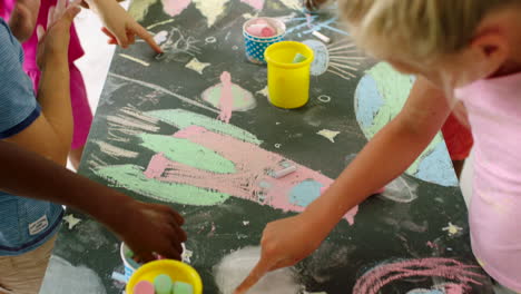 children drawing with chalk on a table