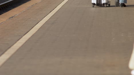 Close-up-of-a-traveler's-feet-walking-on-a-platform-with-a-suitcase