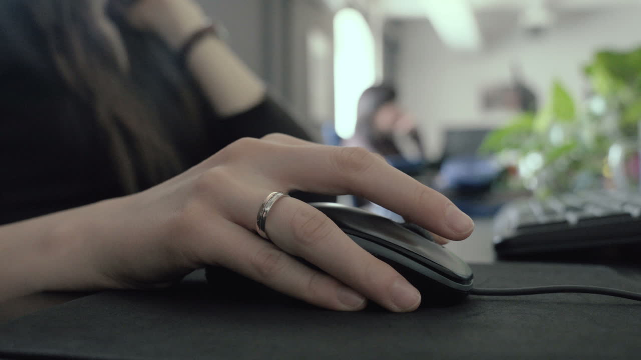 imágenes de bajo contraste de la mano de una mujer haciendo clic y desplazándose con un mouse en la oficina