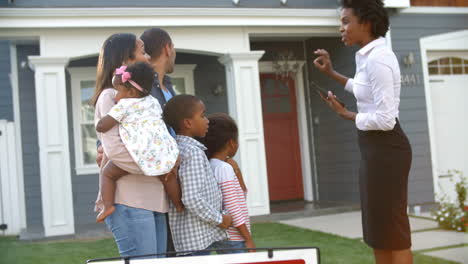 Realtor-Stands-Outdoors-Showing-Family-Around-House-For-Sale