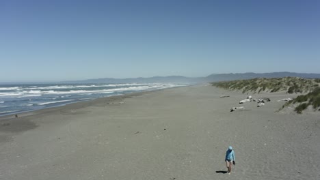 Person-walking-alone-on-a-wide-open-beach