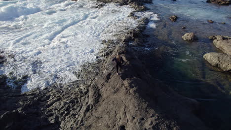Adventurous woman standing on volcanic rocks near a natural pool in Gran Canaria, Spain