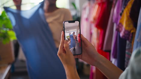 dos amigos comprando ropa en una tienda de moda tomando un video del vestido