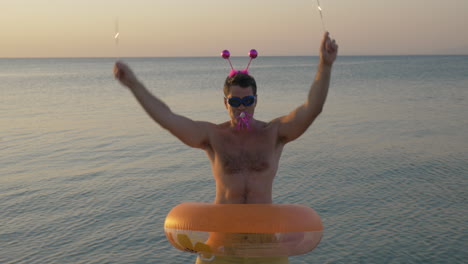 Funny-man-with-rubber-ring-and-sparklers-dancing-on-beach