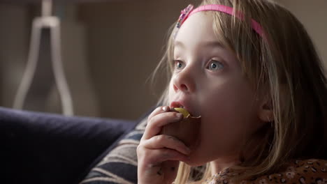 little girl taking a big bite of a chocolate egg treat