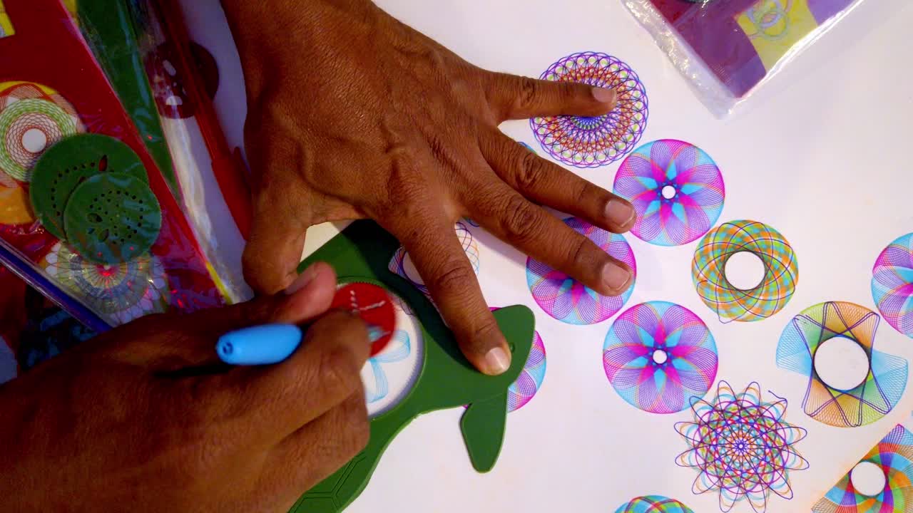 Mature hands drawing detailed colorful floral and geometric mandalas with circular symmetrical design patterns using round stencil