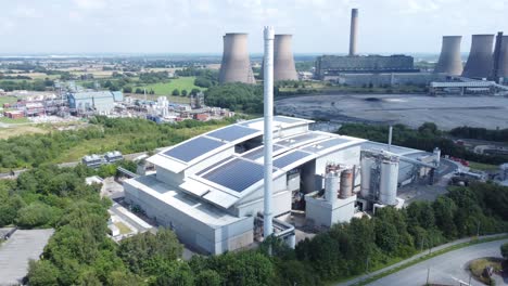 Instalación-Solar-Limpia-En-La-Azotea-En-La-Vista-Aérea-De-Un-Edificio-De-Oficinas-Moderno-Con-Una-Central-Eléctrica-De-Carbón-En-El-Fondo,-Amplia-Toma-En-órbita-Derecha