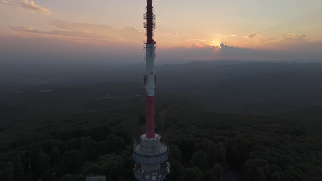 Dramatic aerial view as the sun sets behind the top part of the Kékes TV Tower with the mysterious Mátra Mountains in the background in Hungary