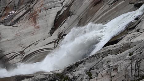 rhone powerful waterfall in rocks near its glacier source at the top of the alps, valais, switzerland