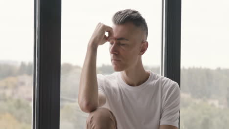 sad man sitting at window worrying about something