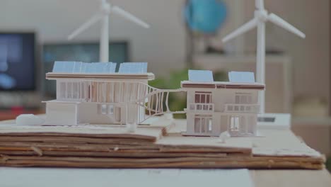 close up of man's hand putting the solar panel on the roof of a small model house