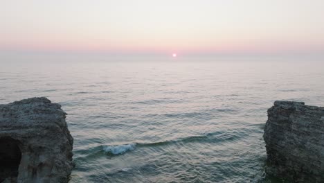 beautiful aerial view of vibrant high contrast sunset over calm baltic sea, clouds at the horizon, karosta war port concrete coast fortification ruins at liepaja, wide drone shot moving forward low