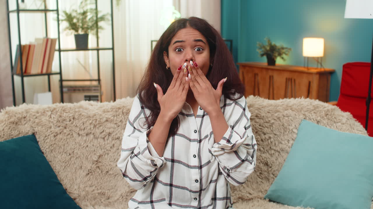 Indian woman shocked by unexpected news hands on cheeks wide eyes wow surprise reaction emotional