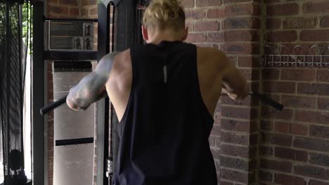 hombre musculoso en el gimnasio en casa ejerciendo la máquina de cable de ejercicio de espalda thurster