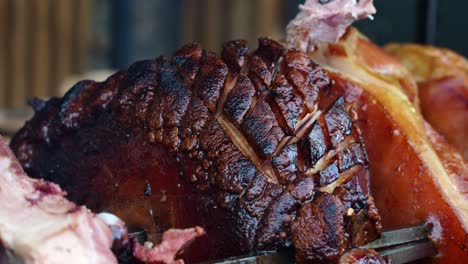 Close-up-of-juicy-roasted-beechwood-smoked-ham-rotate-above-grill-on-skewer