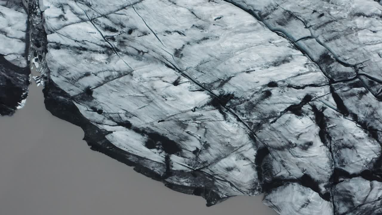 Top down of Iceland glacier with melting pool of brown water, Sólheimajökull