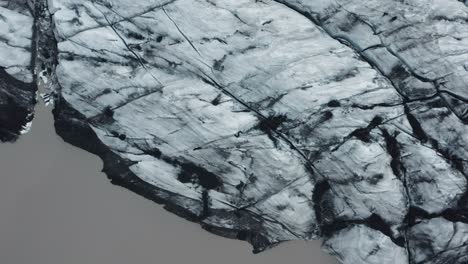 top down of iceland glacier with melting pool of brown water, sólheimajökull