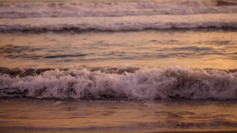 Slow-motion-close-up-of-waves-lapping-on-the-shore-at-sunset