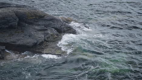 Waves crashing against rugged rocks on a calm coastal day