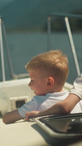 joyful little kids look around riding motorboat on windy day. happy brother and sister sail yacht in ocean bay on summer vacation. children life