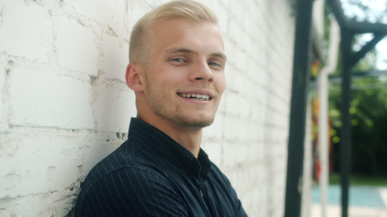 Smiling Man Leaning Against a Brick Wall