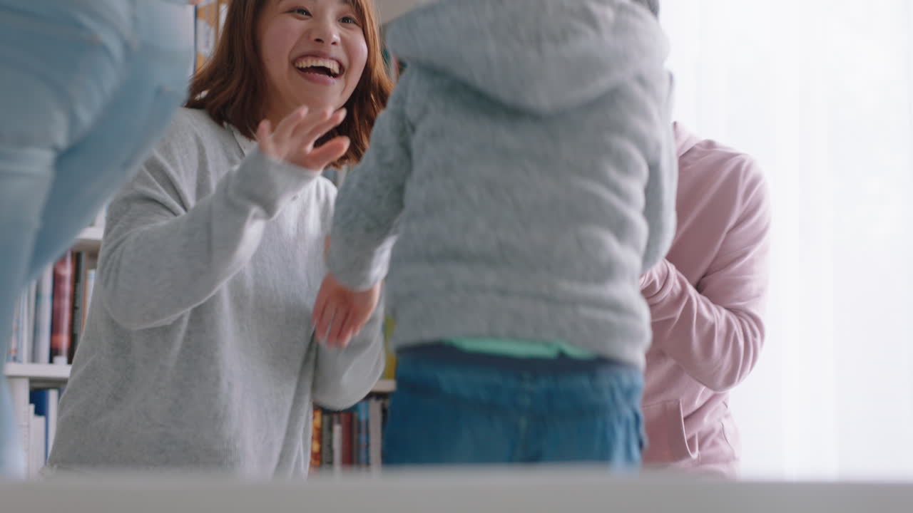happy asian family dancing at home having fun dance celebrating together little children celebrate with mother and father enjoying exciting weekend 4k footage