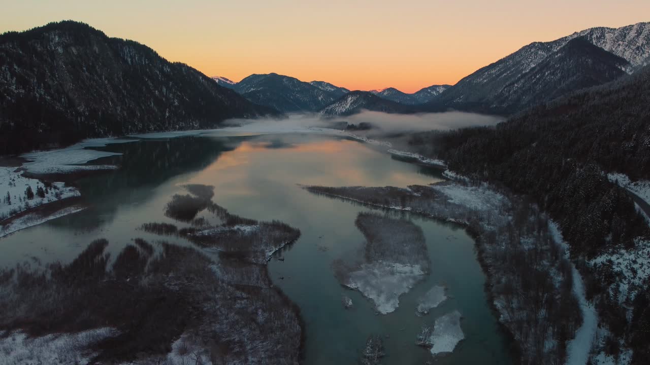 Scenic Bavarian Austrian alps mountain river valley with fresh water at Sylvensteinspeicher by sunshine sunset, winter snow riverbed, trees and forest and mountains