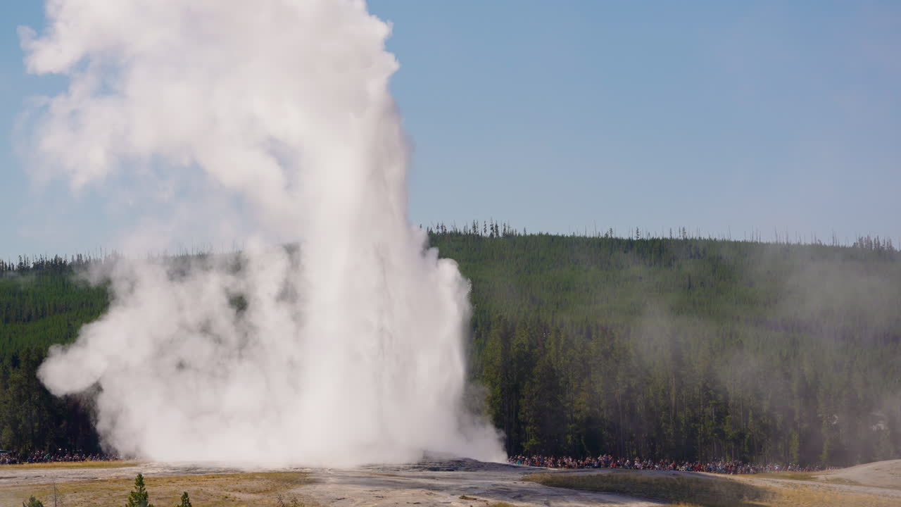 Old Faithful geyser erupting with a crowd of spectators in Yellowstone National Park