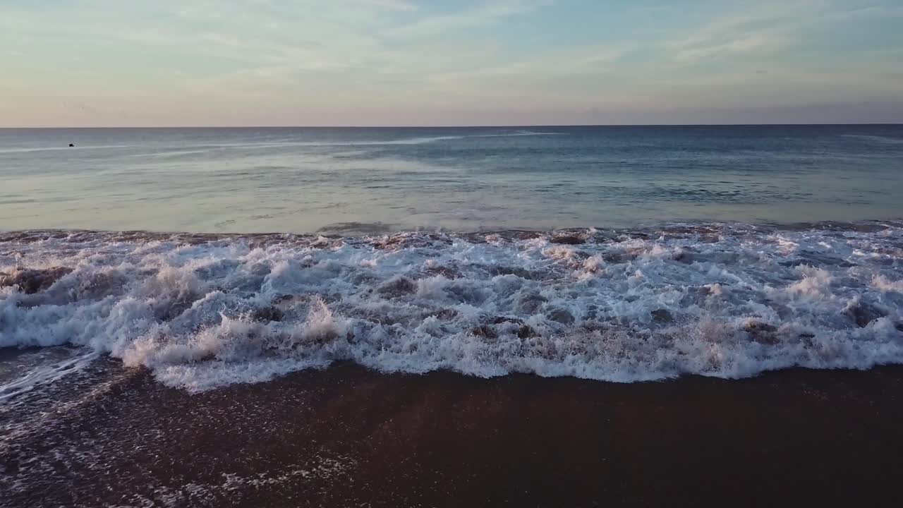 Aerial dolly out of blue ocean waves crashing at beach seaside at day
