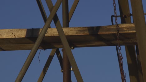 antigua estructura de molino de viento en movimiento, con la luna en un cielo azul, en patagonia, argentina