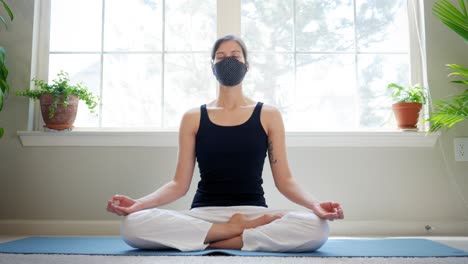 peaceful young female meditates in isolation while wearing a medical mask