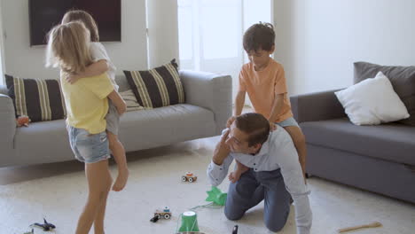 papá caucásico y niños jugando en la sala de estar juntos
