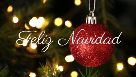 Feliz-navidad-text-against-hanging-christmas-bauble-decoration-against-spots-of-light