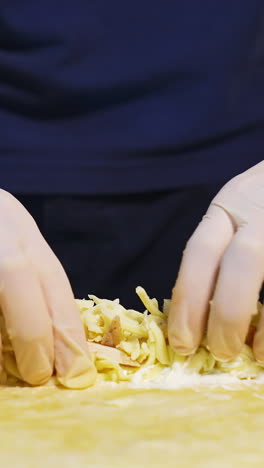 chef prepares pita bread. professional cook is putting cheese and chopped cucumbers into pita. fast food. caucasian cuisine. close-up. vertical video