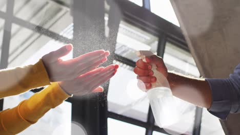 Animation-of-light-spots-over-diverse-people-disinfecting-hands