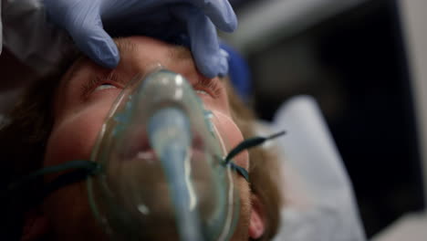 médico con guante examinando los ojos del paciente masculino