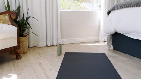 yoga mat on wooden floor in bright bedroom with cozy decor and natural light, copy space