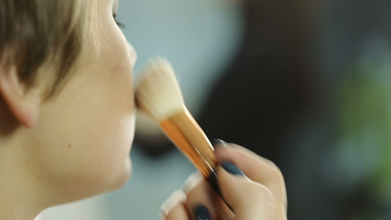 Girl using makeup brush. Woman applying dry cosmetic tonal foundation on face