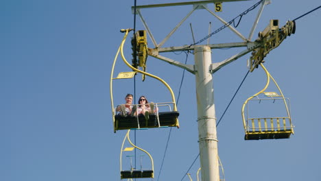 A-Couple-Of-Friends-Ride-On-A-Ski-Lift-Holidays-In-The-Mountains-In-The-Summer-4K-10-Bit-Video