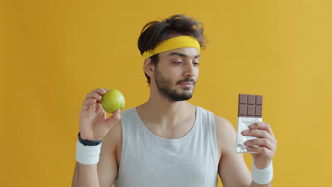 man choosing between an apple and chocolate bar