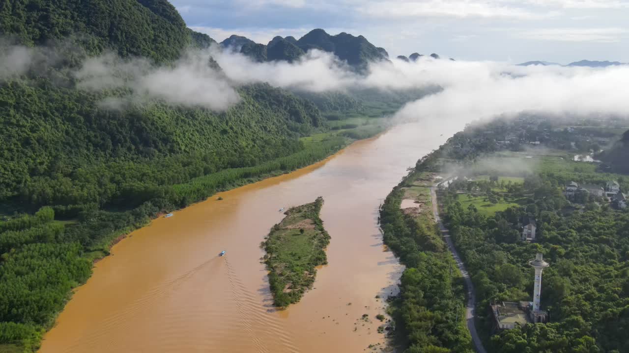 Drone follow up the small boat running in the river revealing beautiful cloudy green mountain range in early morning in Phong Nha Viet Nam