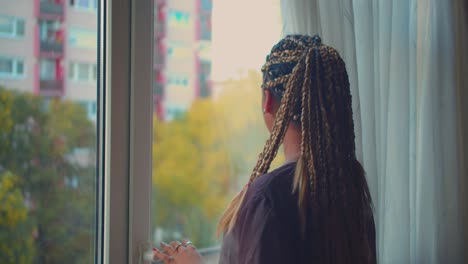 Joven-Y-Bonita-Mujer-Afroamericana-Con-Trenzas-Y-Rastas-Abriendo-Las-Cortinas-De-La-Ventana-En-La-Mañana-De-Verano