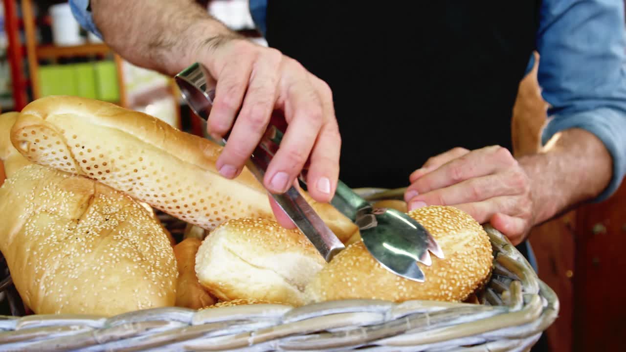 Male staff arranging a loaf of bread in wicker basket